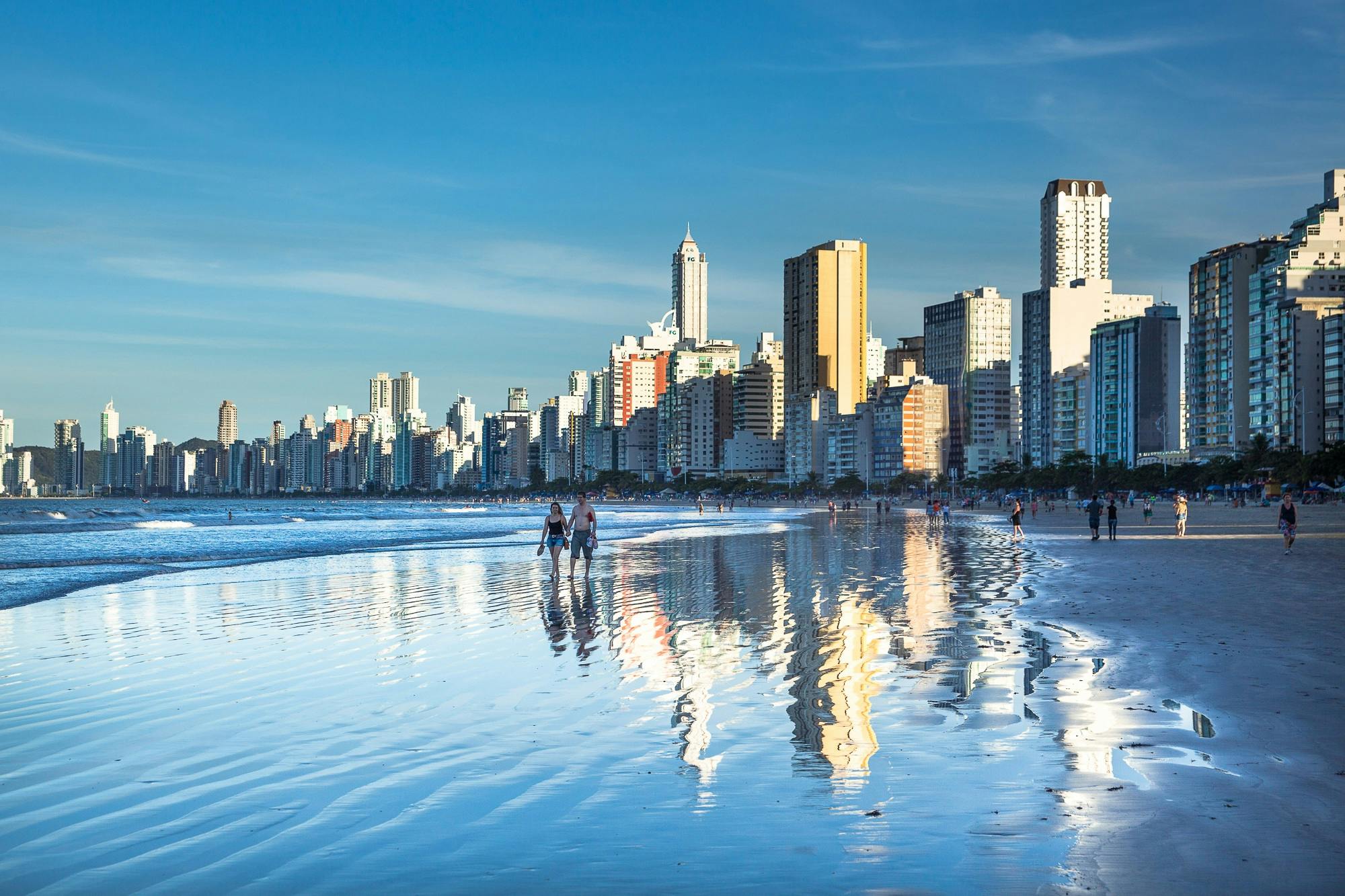 Horizonte promissor: investimentos imobiliários em Santa Catarina movimentam bilhões e atraem investidores 1 Stunning view of Balneário Camboriú's modern skyline reflecting on the beach at daytime.